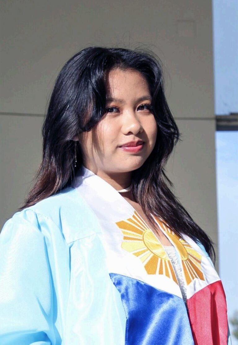 Samantha standing, dressed in academic regalia.